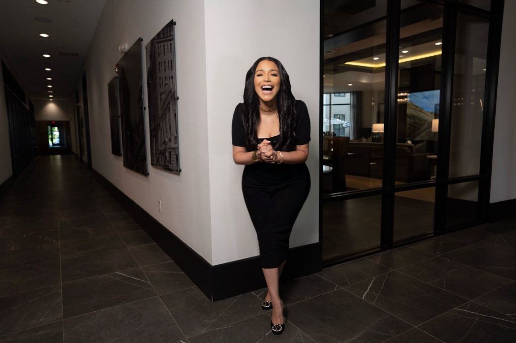 Erika Baez-Grimes laughing in a corporate hallway, available to book to speak